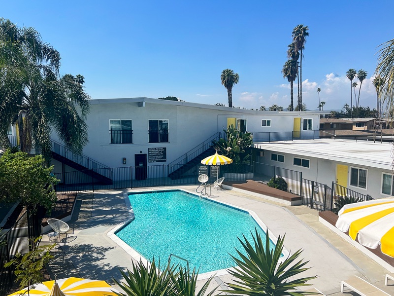 Elevated view of the Rock Ridge pool courtyard with the two-story building, black iron fencing and palm trees