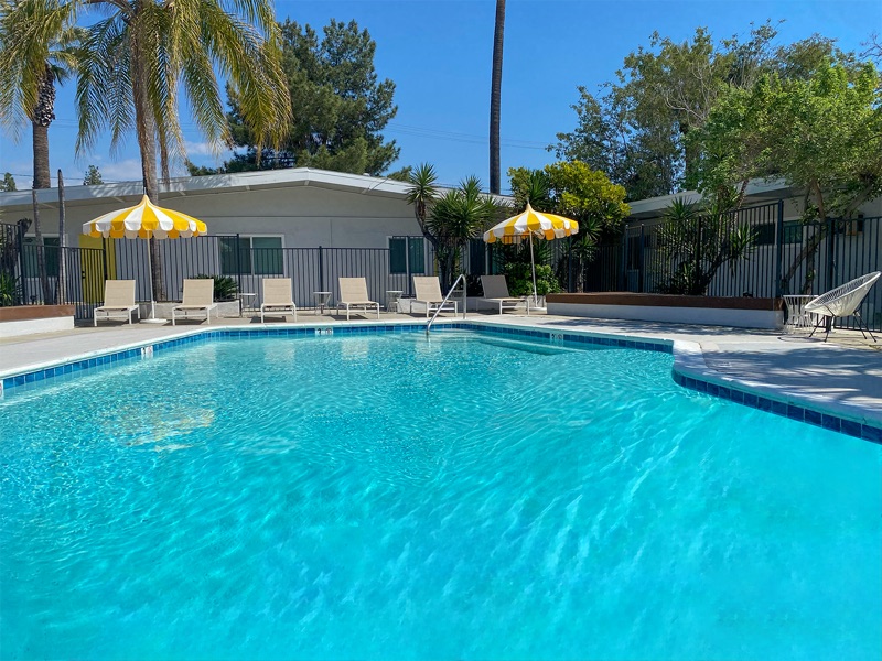Pool and sun deck at Rock Ridge with lounge chairs under yellow-and-white umbrellas